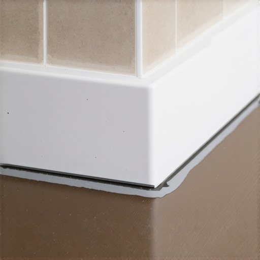 Close-up of a waterproofed curbless shower floor and baseboard transition.